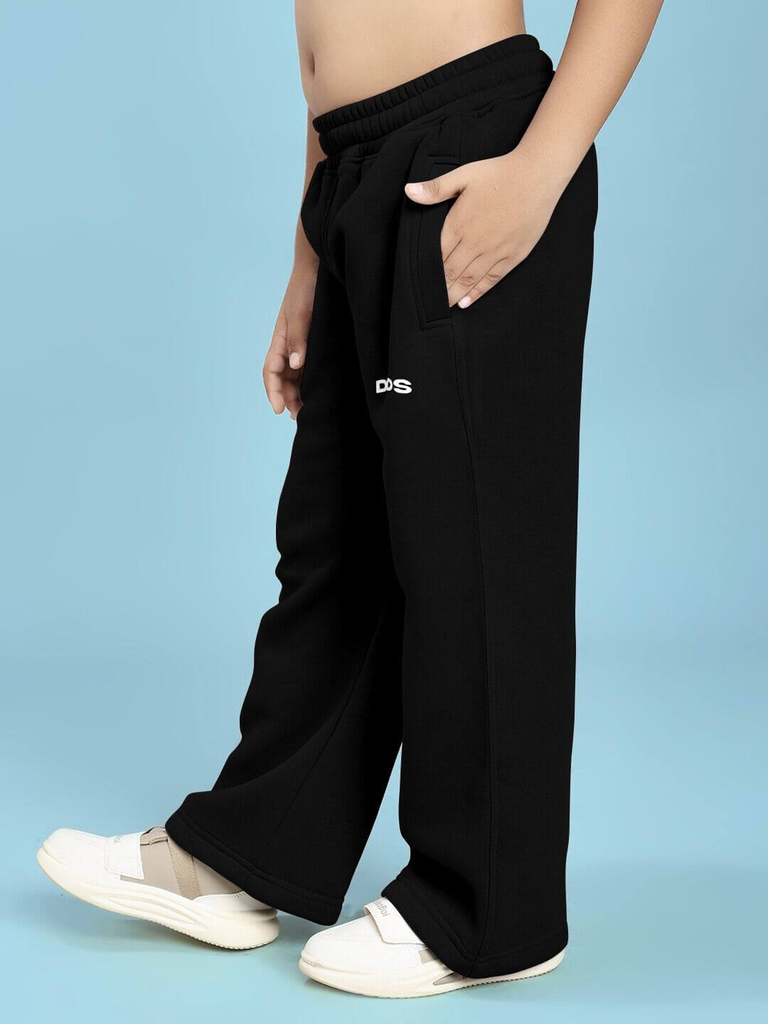 Child wearing JUDY NICK ZOOTOPIA FLEECE CO-ORD FOR BOYS AND GIRLS BLACK pants with white shoes standing against a blue background.