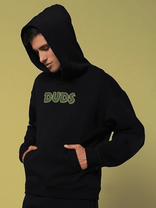 Model wearing JUDY NICK ZOOTOPIA FLEECE HOODIE BLACK with hands in pocket, showcasing front design in casual pose.