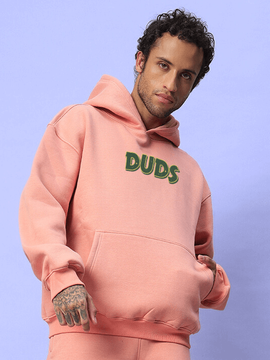 Man wearing JUDY NICK ZOOTOPIA FLEECE HOODIE PEACH in cozy streetwear style with playful design and soft peach tone.