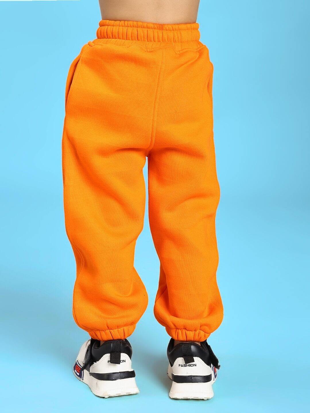 Child wearing JUMPYJOY CO-ORD FOR BOYS AND GIRLS WHITE ORANGE pants with sneakers.