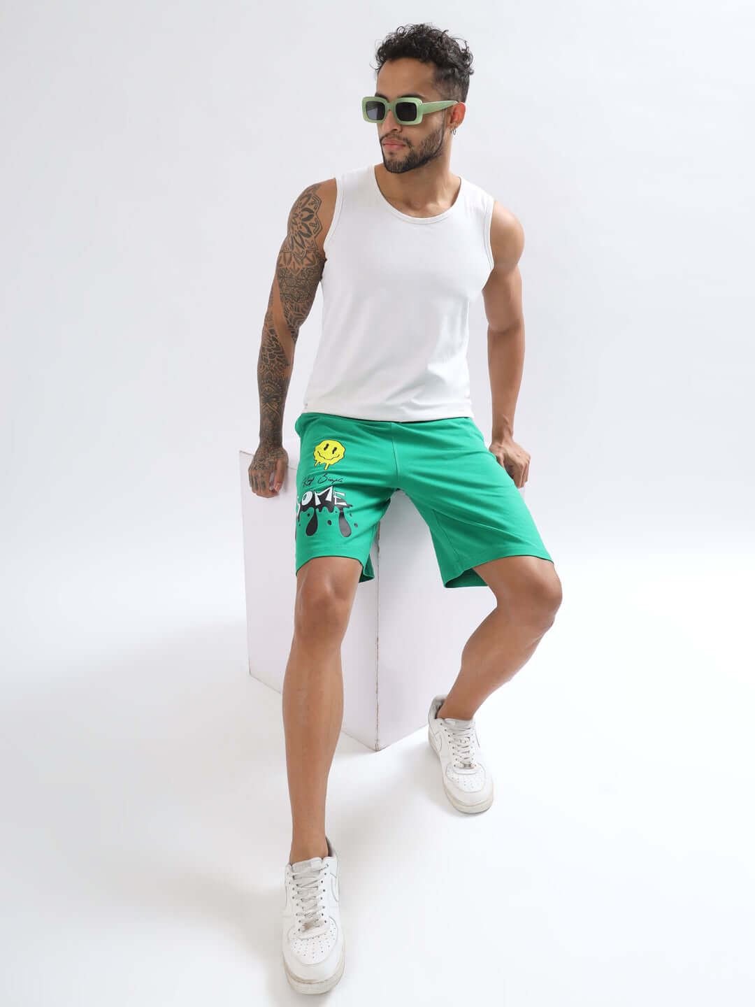 Model wearing green KEEP SIMPLE SOME regular fit shorts, white tank top, and sunglasses, showcasing casual summer style.