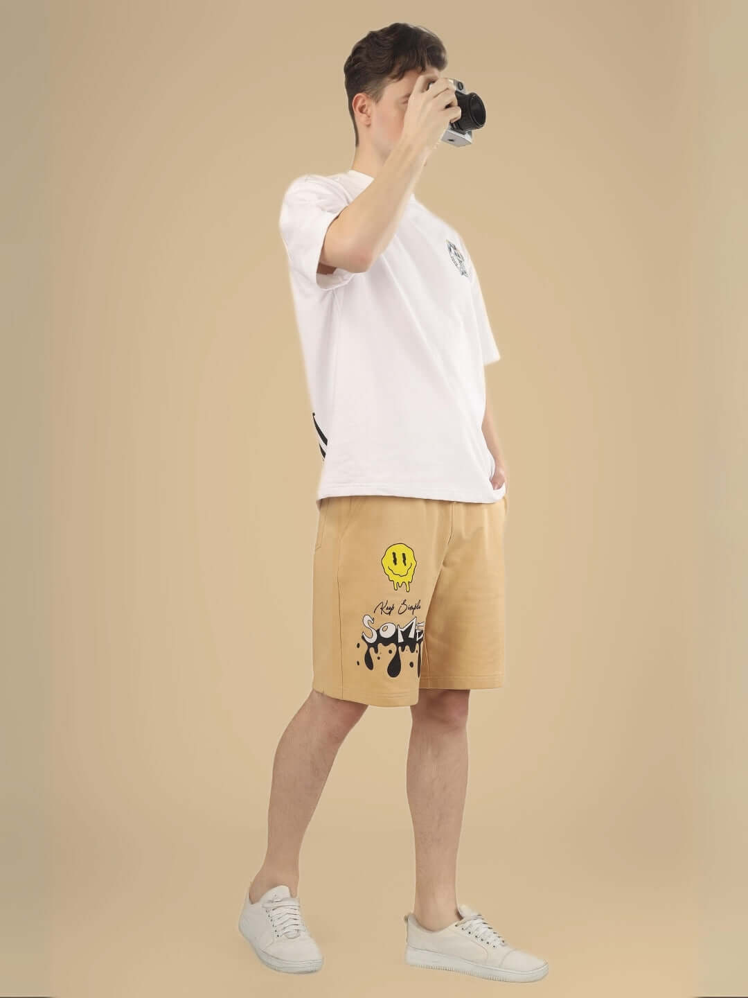 Beige regular fit shorts with graphic design, shown on model wearing white t-shirt and shoes, customizable size option available.