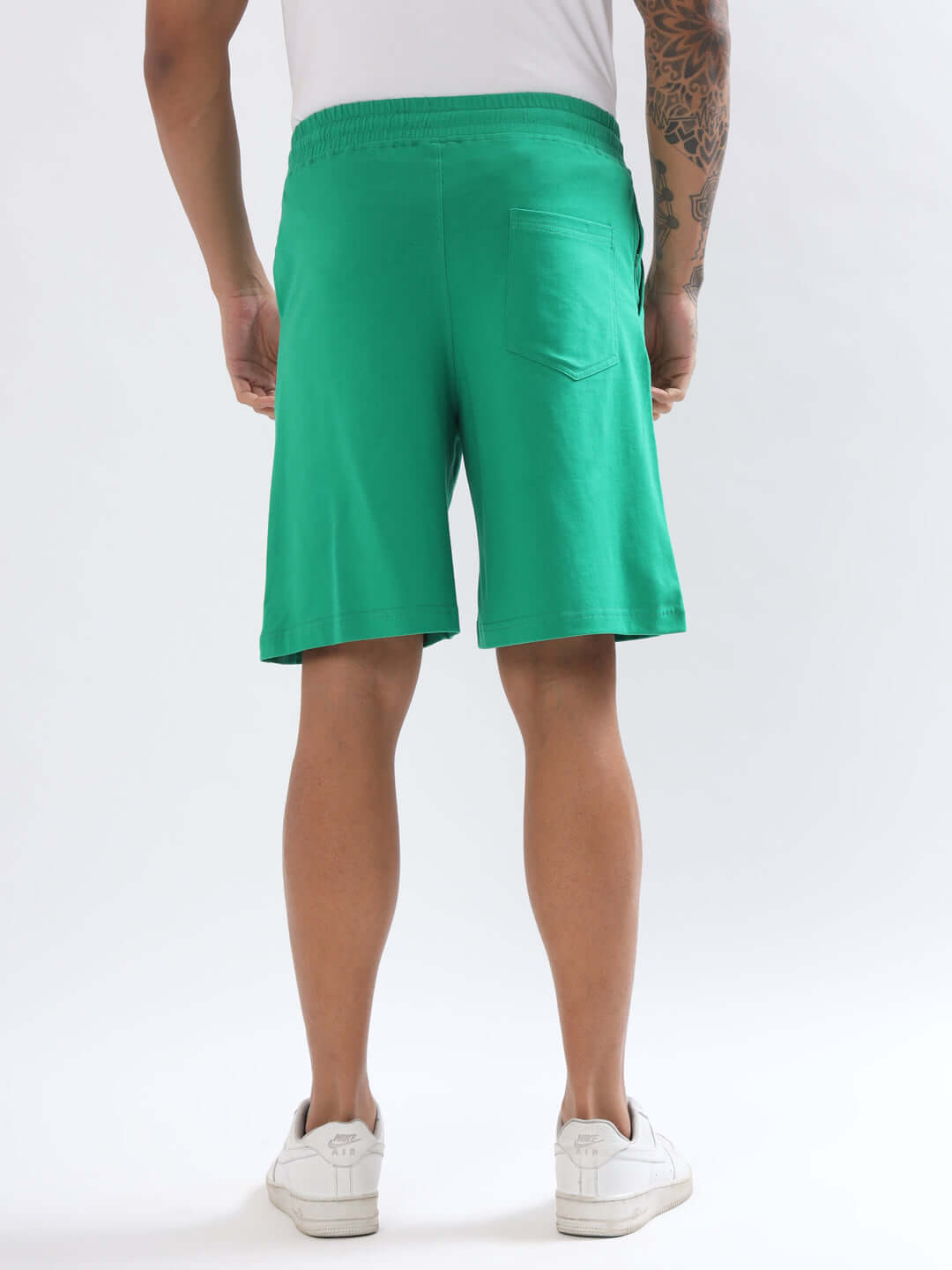 Back view of a person wearing green regular fit shorts with a casual style, featuring an elastic waistband and a rear pocket.