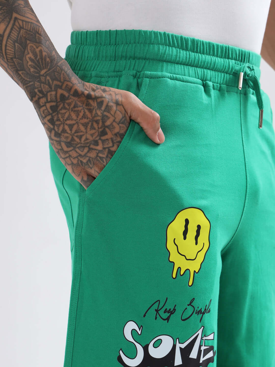 Person wearing green regular fit shorts with smiley face design, showcasing Keep Simple text.