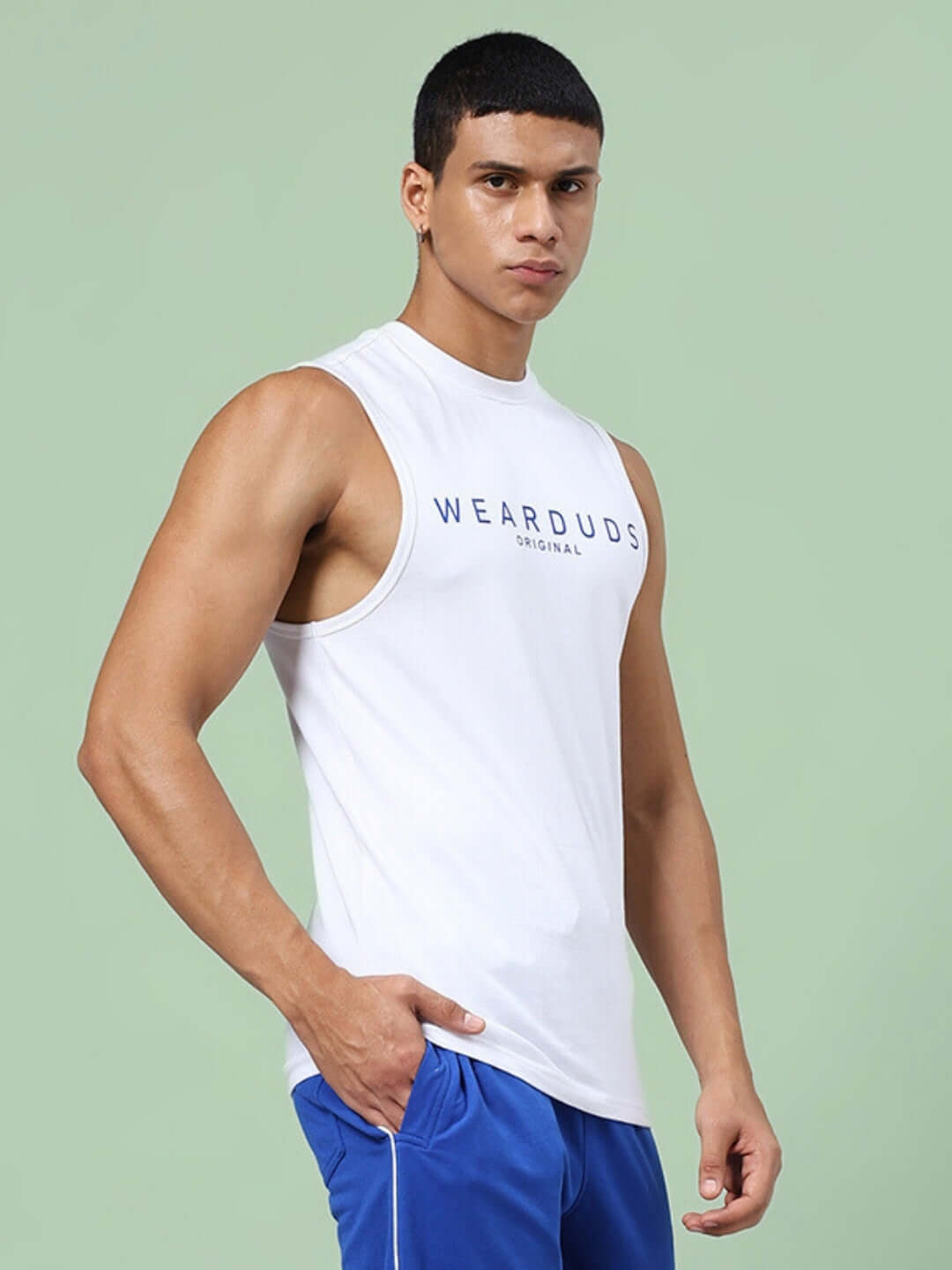 Man wearing a white sleeveless KICKSHAW GYM T-shirt with 'Wear Duds' text, showcasing a custom fit option.