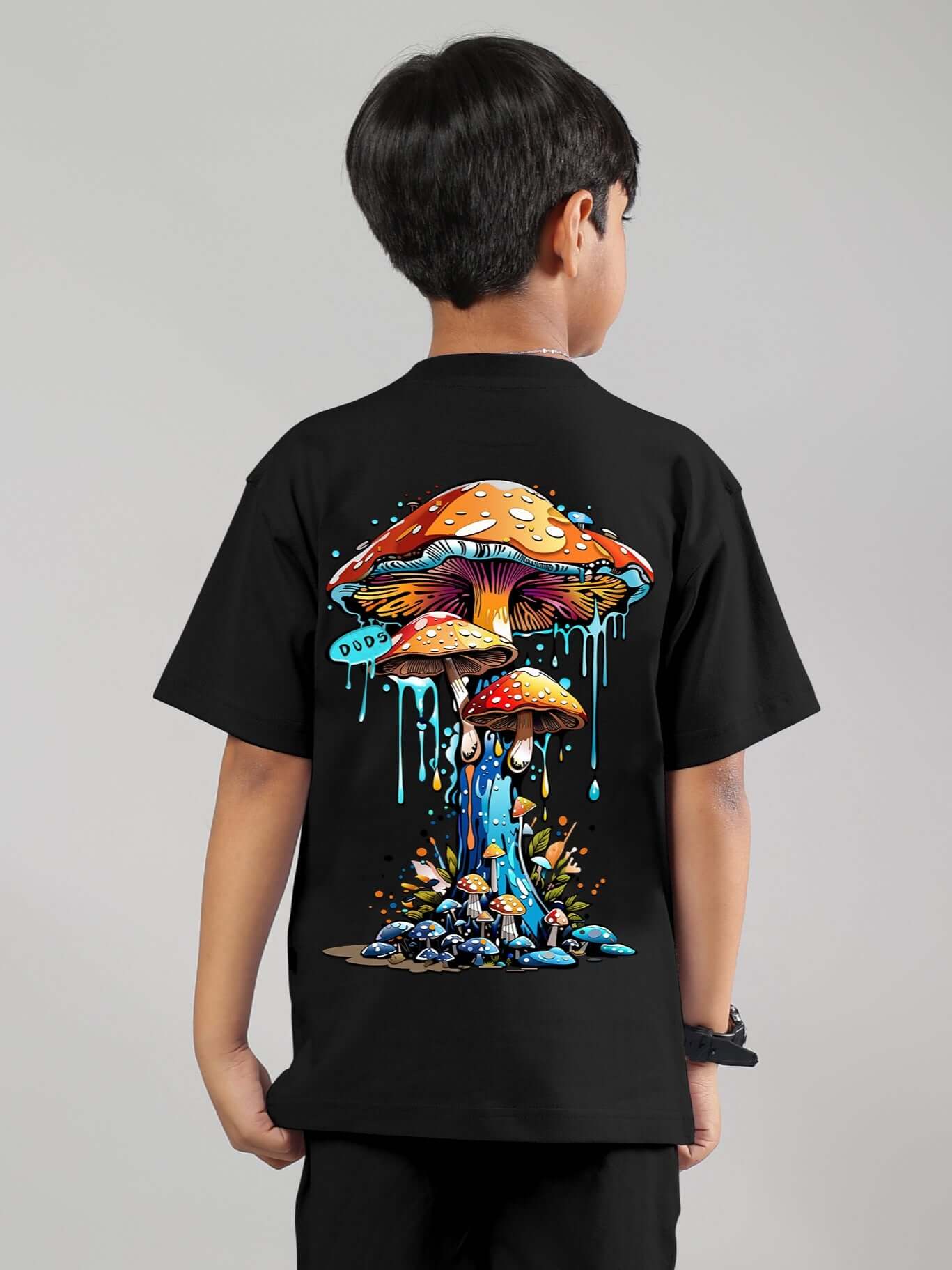 Boy wearing a black fantasy mushroom t-shirt with colorful graphic design, suitable for boys and girls, made to order by DUDS.