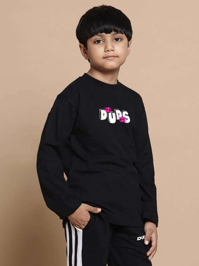 Child wearing black I'M OK CO-ORD set with 'DUPS' logo, featuring relaxed fit joggers and an elasticated waistband, ideal for boys and girls.