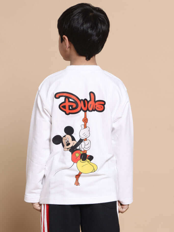 Child wearing a white long-sleeve shirt with cartoon character graphic and logo on the back, featuring black pants with side stripes.