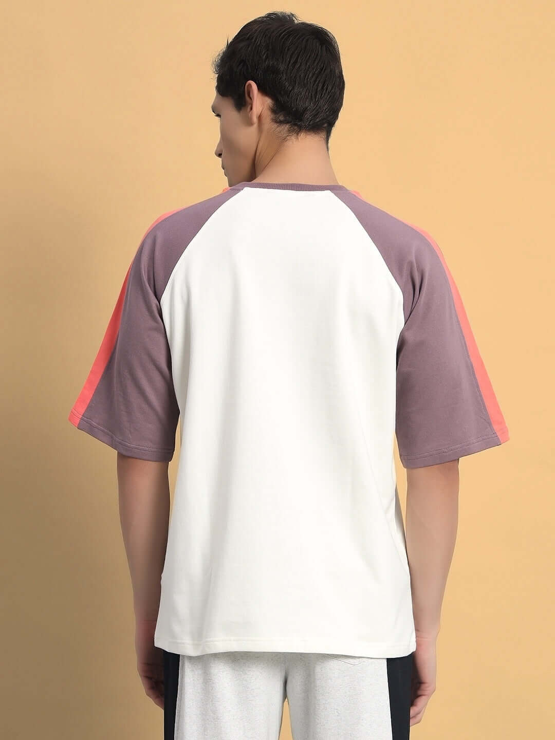 Back view of a model wearing Kingdom Raglan Blocked Oversized T-shirt in off white and violet, made from premium cotton and elastane.
