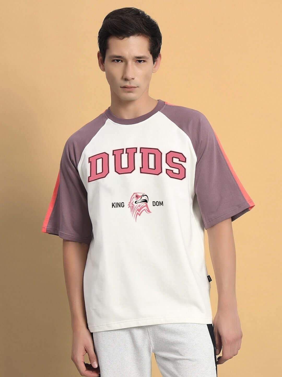 Model wearing KINGDOM Raglan Blocked Oversized T-Shirt in off white and violet with 'DUDS' text, made of premium cotton French Terry.