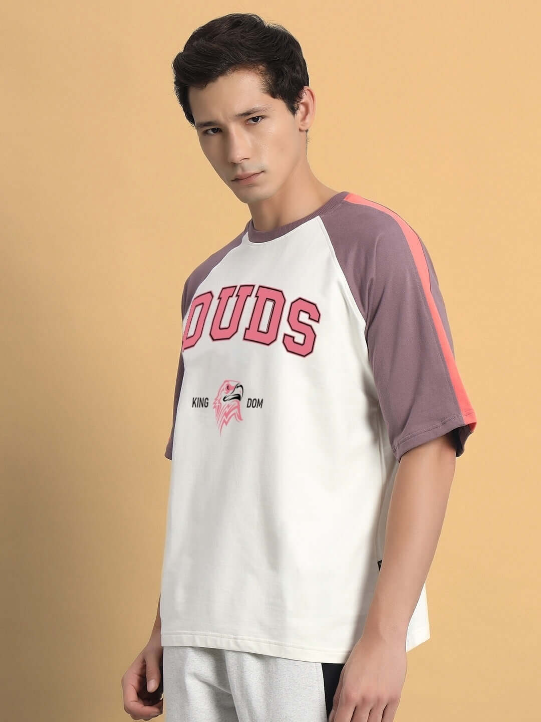 Model wearing 'Kingdom Raglan Blocked Oversized T-Shirt' in off white and violet, featuring premium cotton fabric.
