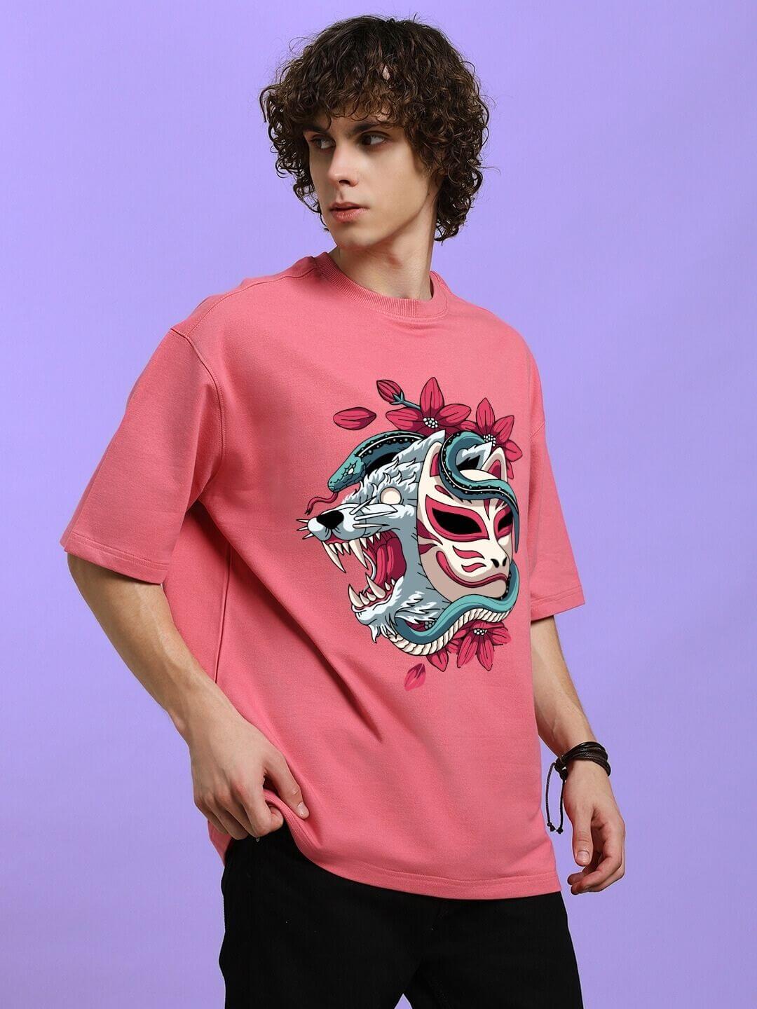 Model wearing KITSUNE WOLF PRINTED OVERSIZED T-SHIRT PINK with Japanese-inspired wolf motif in blush pink against purple background.