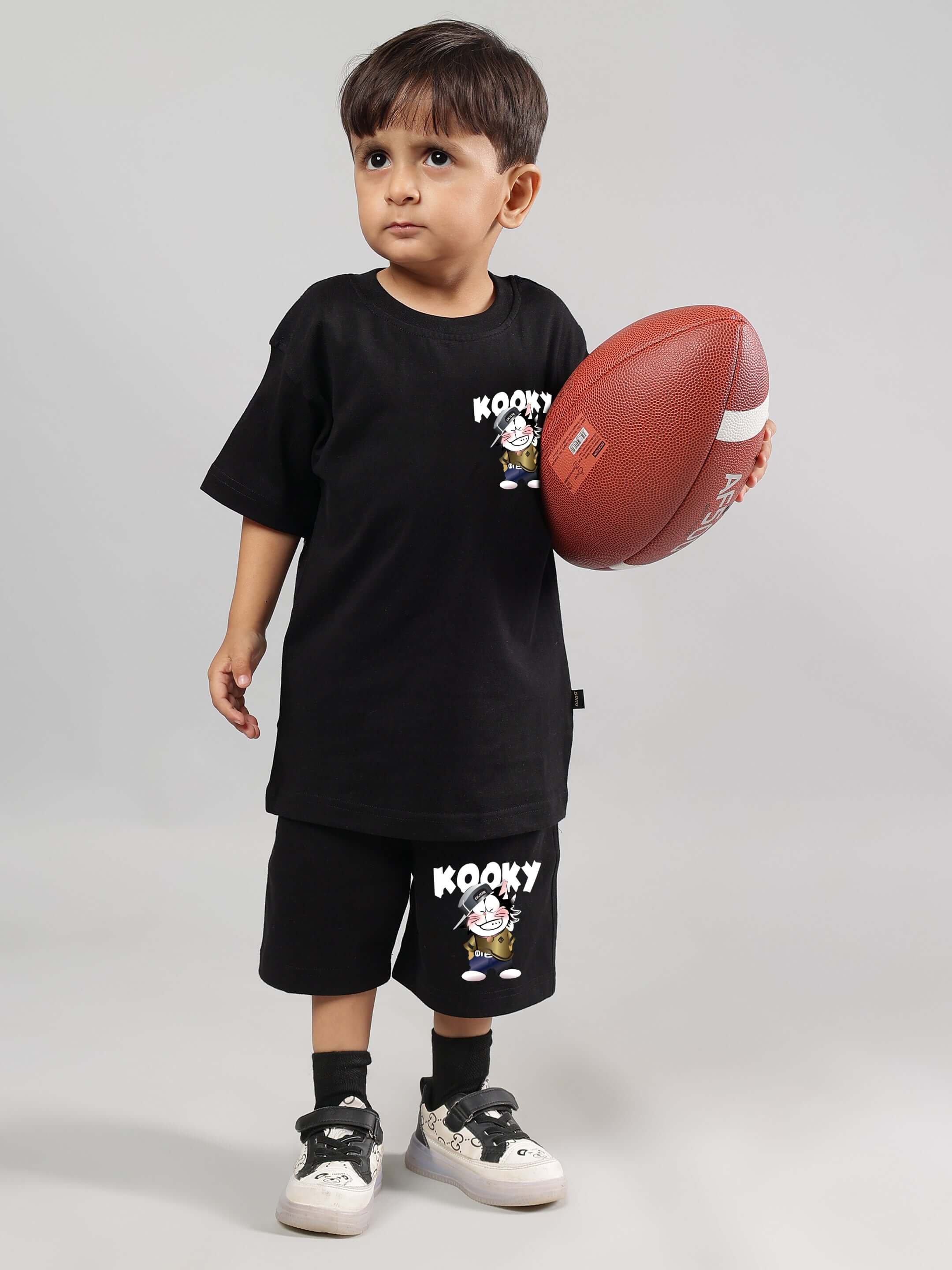 Child wearing KOOKY CO-ORD FOR BOYS GIRLS BLACK holding a football, showcasing premium breathable cotton streetwear for playful style.
