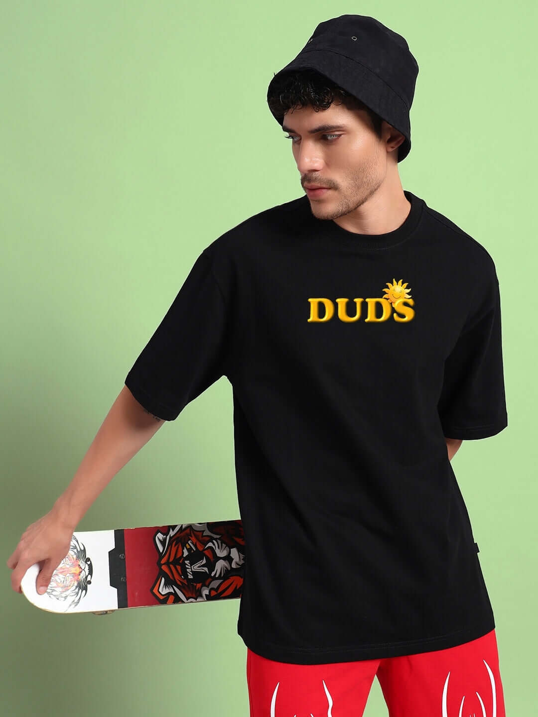 Man wearing a Labubu Monsters Oversized T-Shirt Black, holding a skateboard, stylish streetwear look.