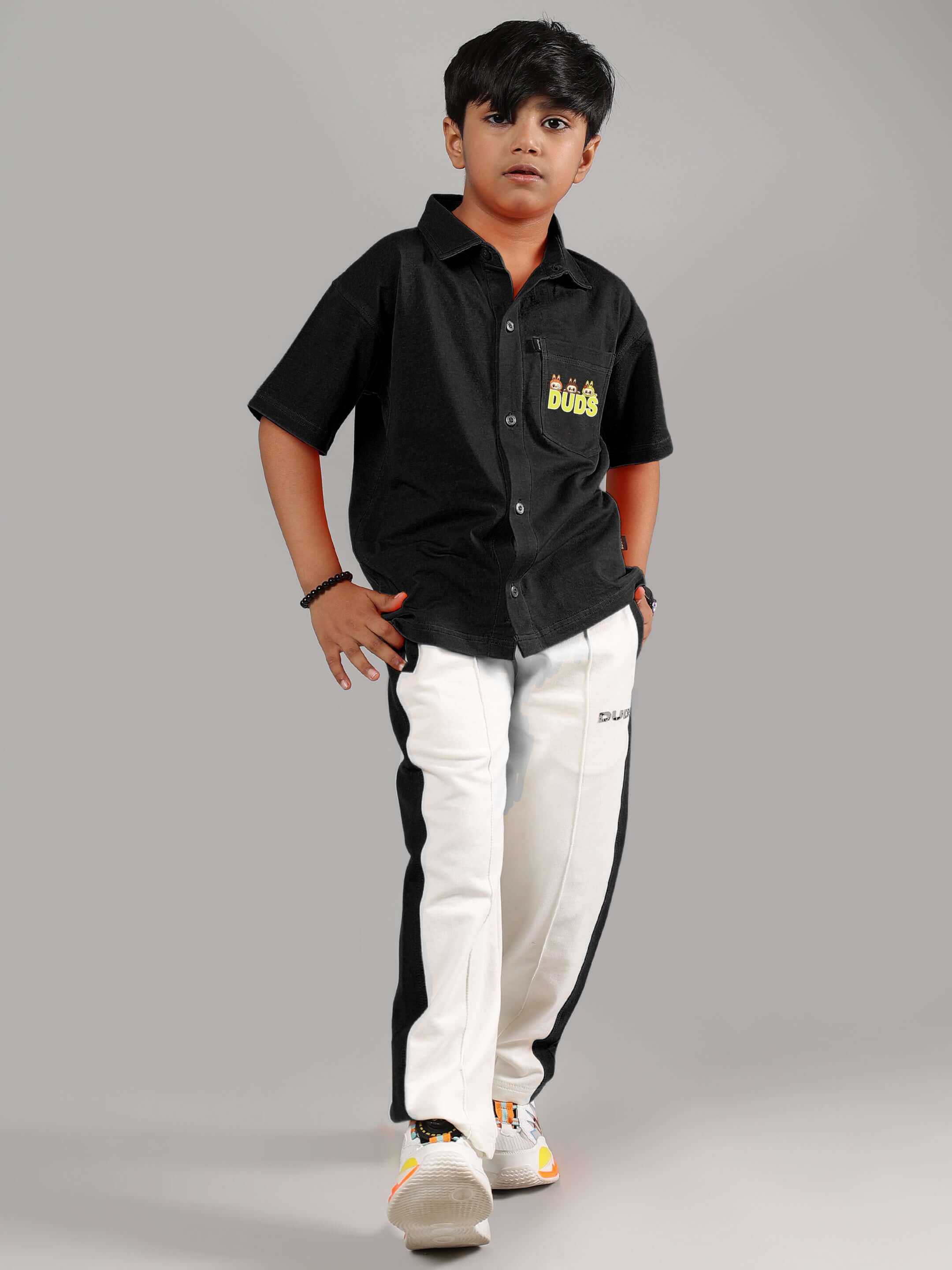 Child in black and off-white Labubu mystery co-ord by DUDS for boys and girls, featuring shorts and short-sleeve shirt.