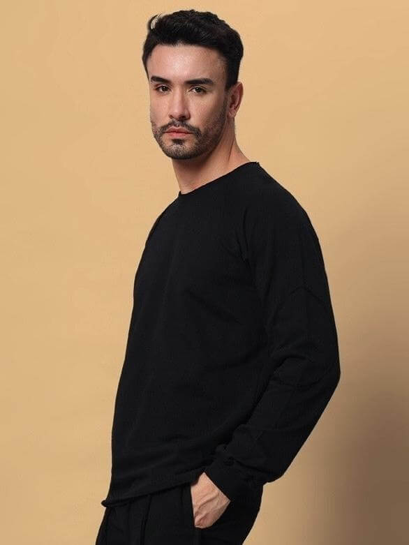 Man wearing a black oversized sweatshirt made from premium cotton French terry lycra, styled in a casual pose against a neutral background.