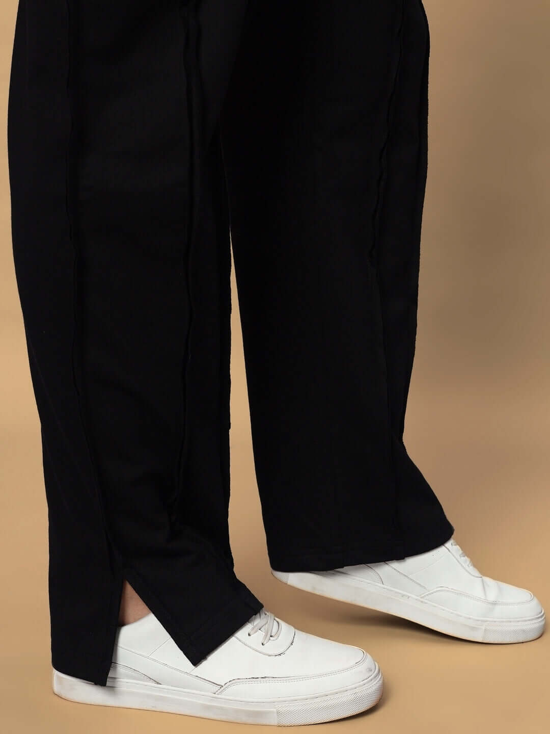 Unisex black joggers with elastic waistband, paired with white sneakers, showcasing the relaxed fit of the LAMINA oversized co-ord set.