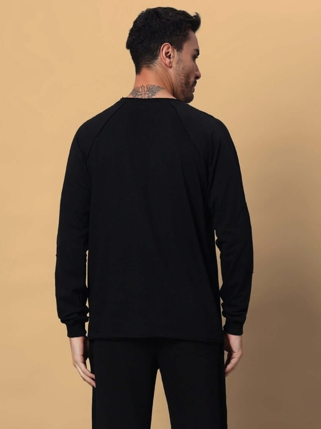 Back view of a black oversized sweatshirt, made from 97% cotton French terry with 3% elastane, featuring a comfortable fit, worn by a man.