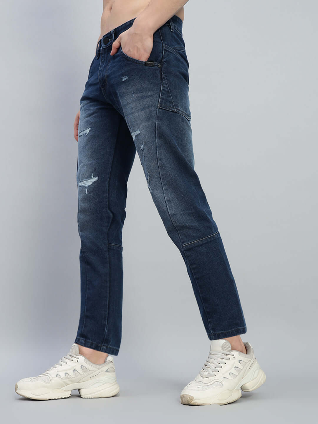 Side view of Lavish Regular Fit Denim Jeans in blue, featuring distressed details, worn with white sneakers.