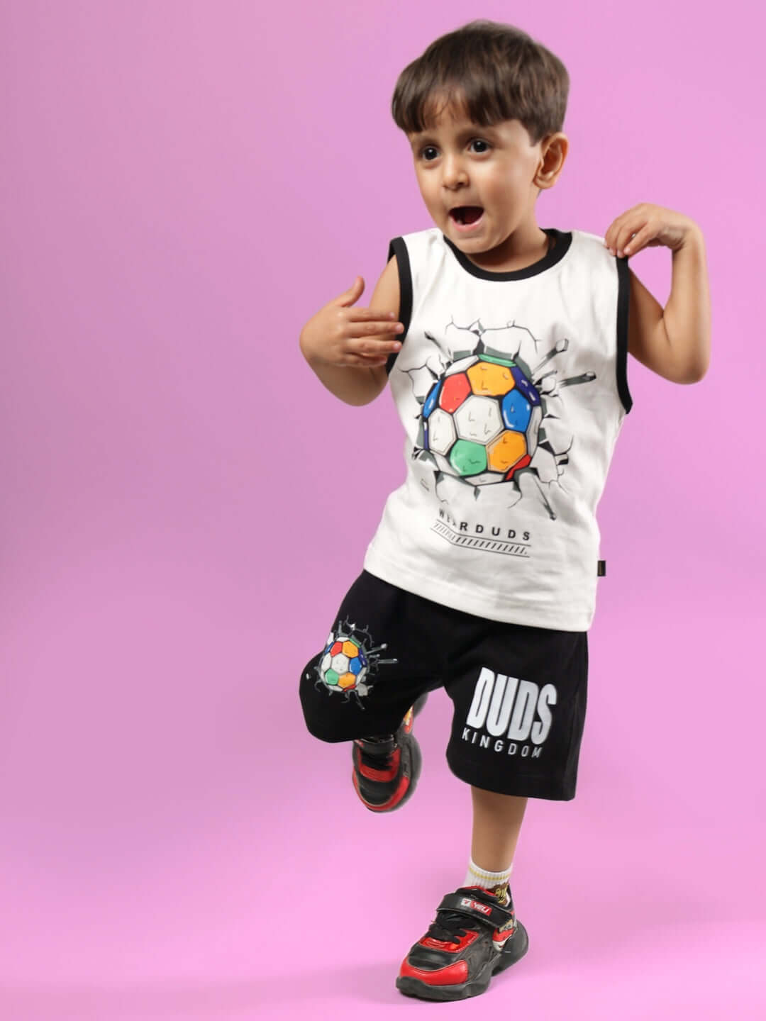 Young child wearing a LAZIO CO-ORD FOR BOYS & GIRLS OFF WHITE-BLACK set, striking a playful pose against a purple background.