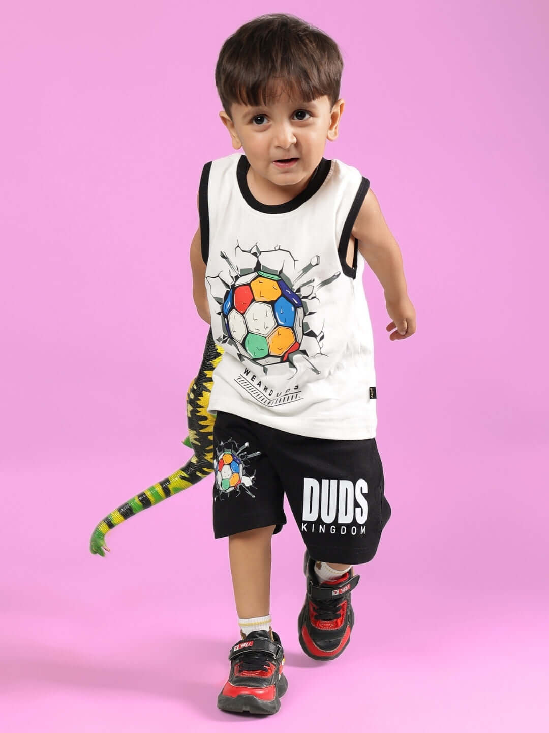 Young boy models in stylish LAZIO Co-ord for boys & girls, featuring an off-white top with soccer ball print and black shorts by DUDS.