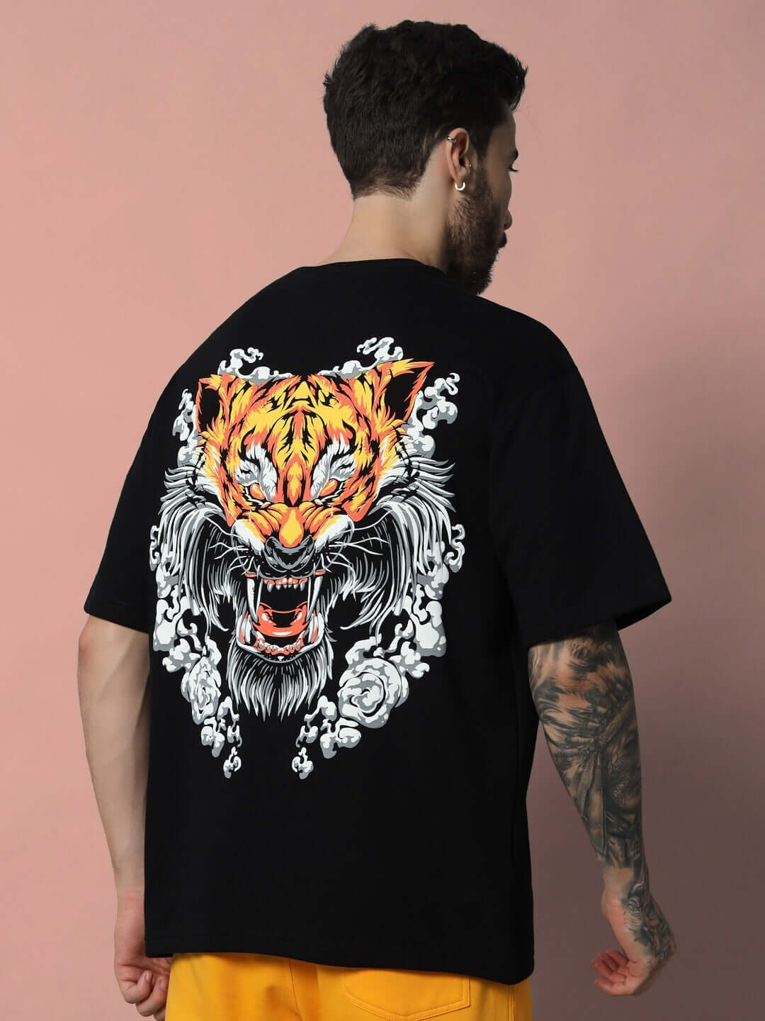 Man wearing black oversized T-shirt with vibrant tiger graphic and intricate design on back, made of premium heavy gauge fabric.