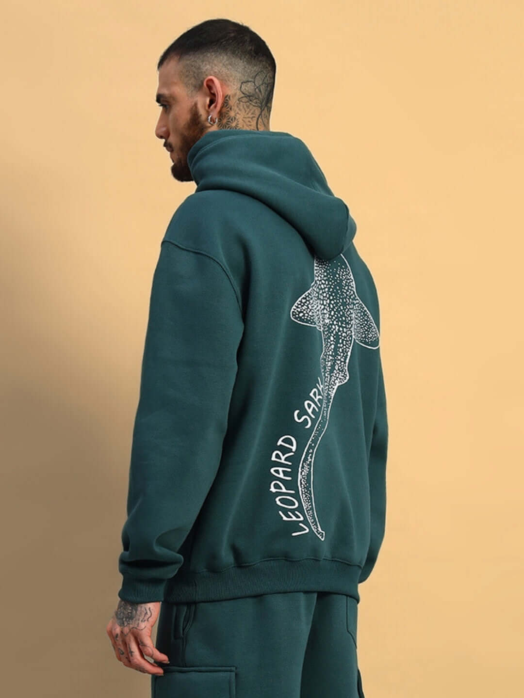 Man wearing LEOPARD SHARK FLEECE HOODIE TEAL GREEN, showing back design with shark illustration.
