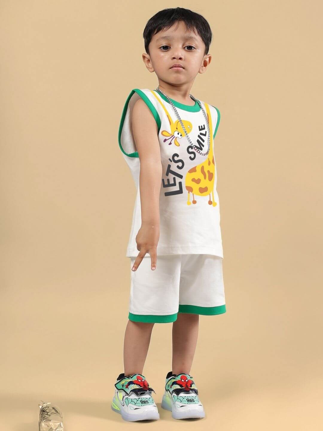 Child wearing LET'S SMILE CO-ORD FOR BOYS AND GIRLS OFF WHITE, featuring giraffe print and green trim, ideal for summer adventures.