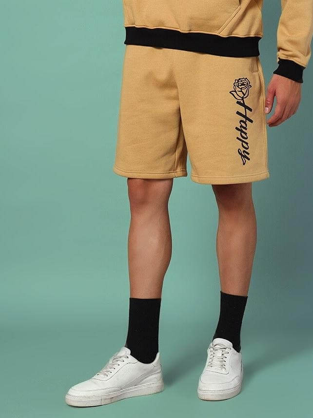 Person wearing HAPPY REGULAR FIT FLEECE SHORTS BEIGE standing against a teal background, showcasing style and comfort.