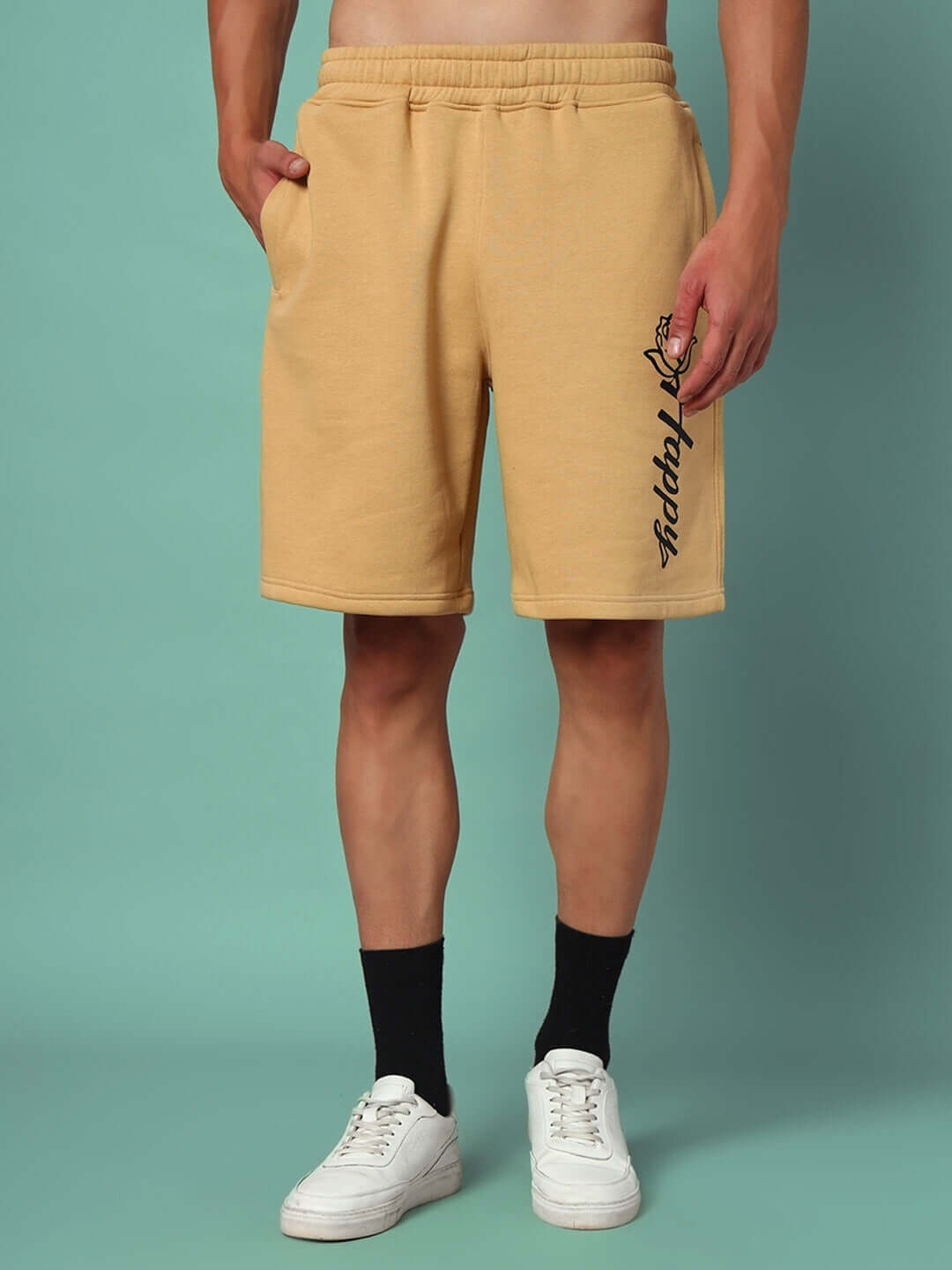 Alt Tag: Model wearing HAPPY REGULAR FIT FLEECE SHORTS BEIGE, showcasing relaxed fit and side pockets against a blue background