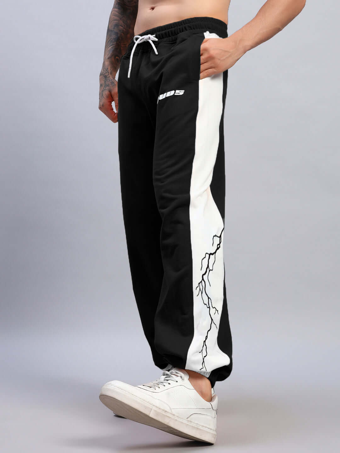 Black and white lightning bolt relaxed fit joggers with customizable size option, made by DUDS, worn by a model.
