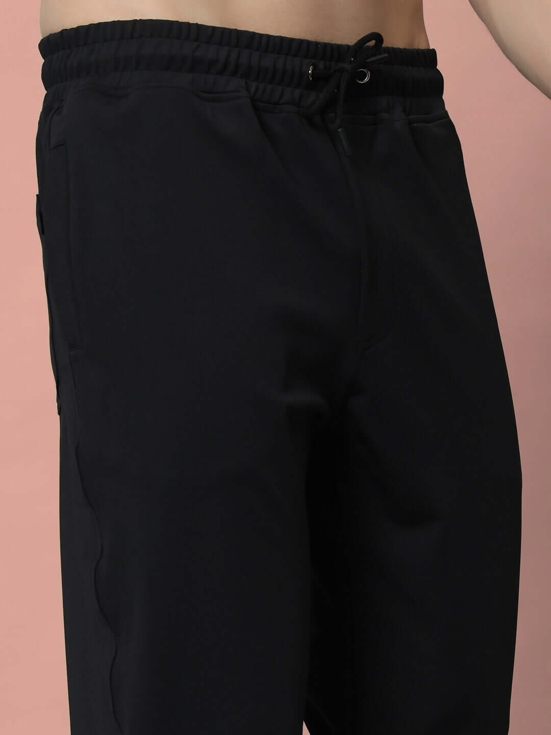 Model wearing black LIMBER Relaxed Pant Jogger with elastic waistband, showcasing comfortable and stylish fit against pink background.