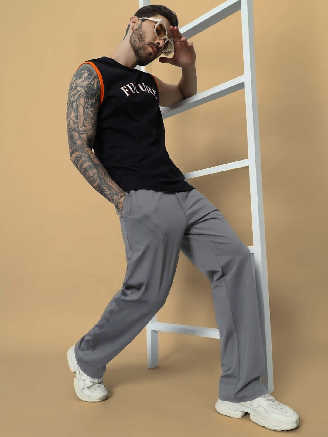 Model wearing grey LIMBER Relaxed Pant Jogger paired with black t-shirt and white sneakers, leaning casually against a ladder.
