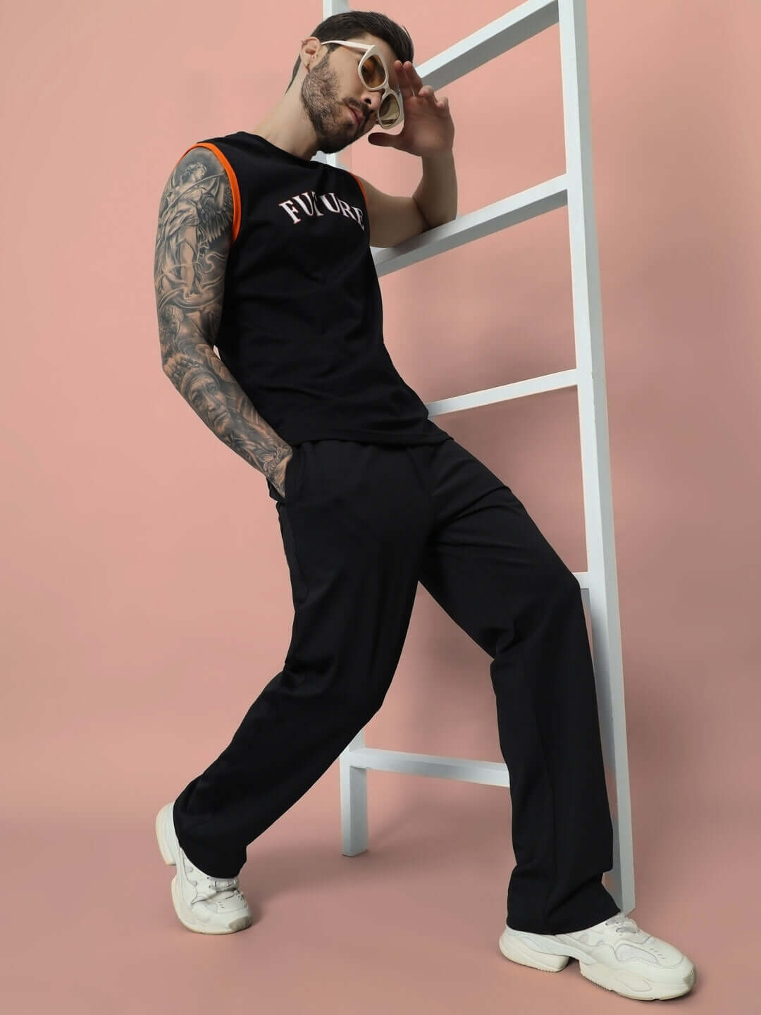 Man wearing Limber Relaxed Pant Joggers in black, showcasing casual style with ladder prop against a pink background.