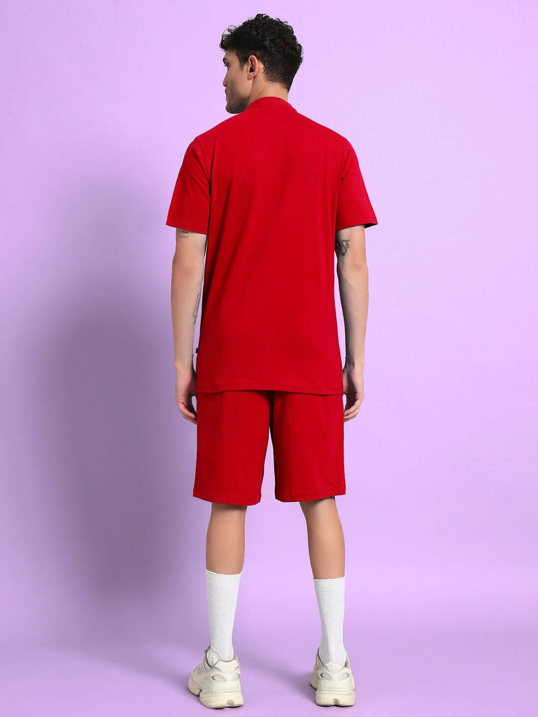 Man wearing LIMBO red co-ord set with premium cotton shirt and shorts, standing against a purple background.