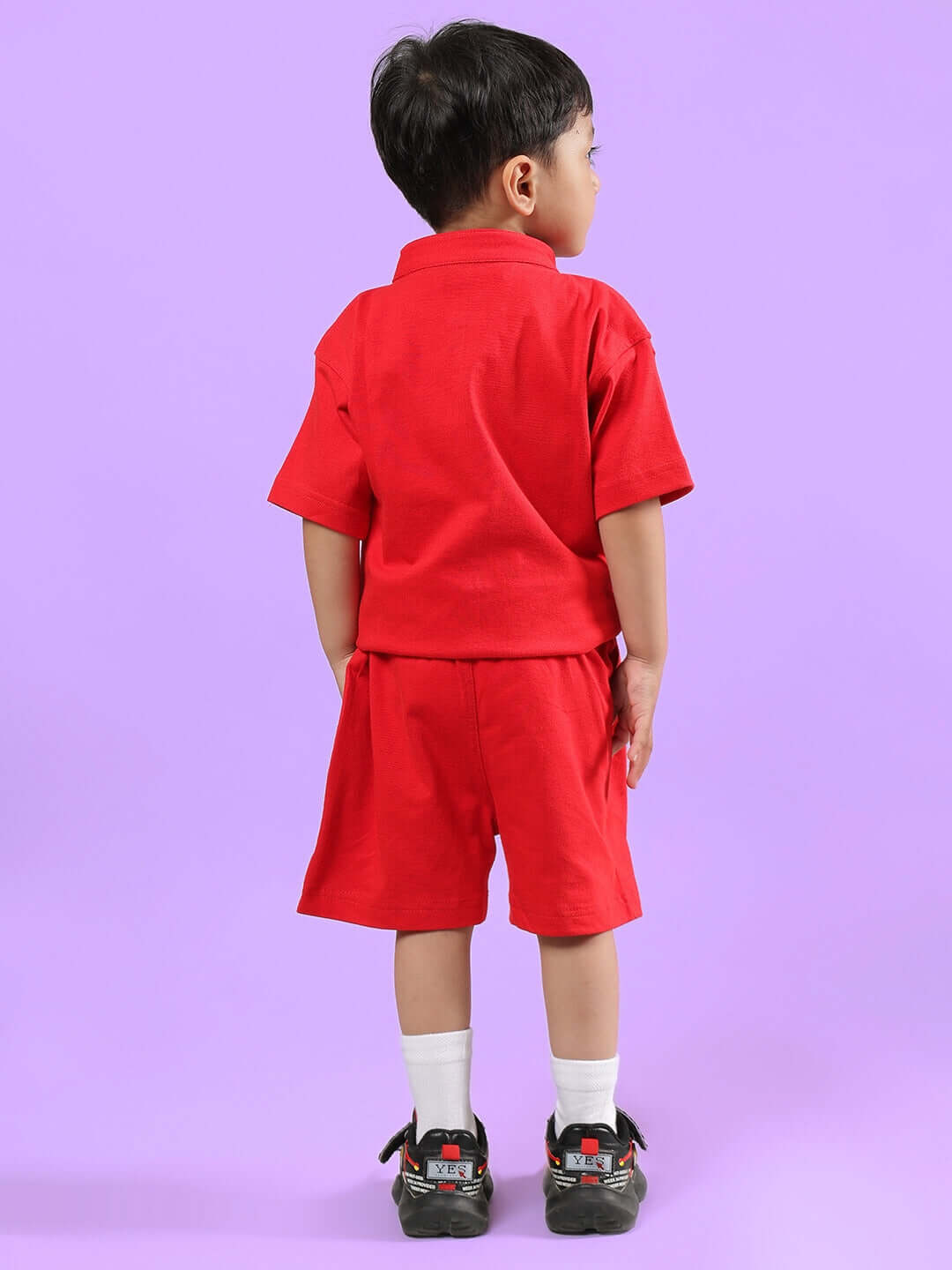 Child wearing LIMBO CO-ORD FOR BOYS & GIRLS RED, back view against purple background.
