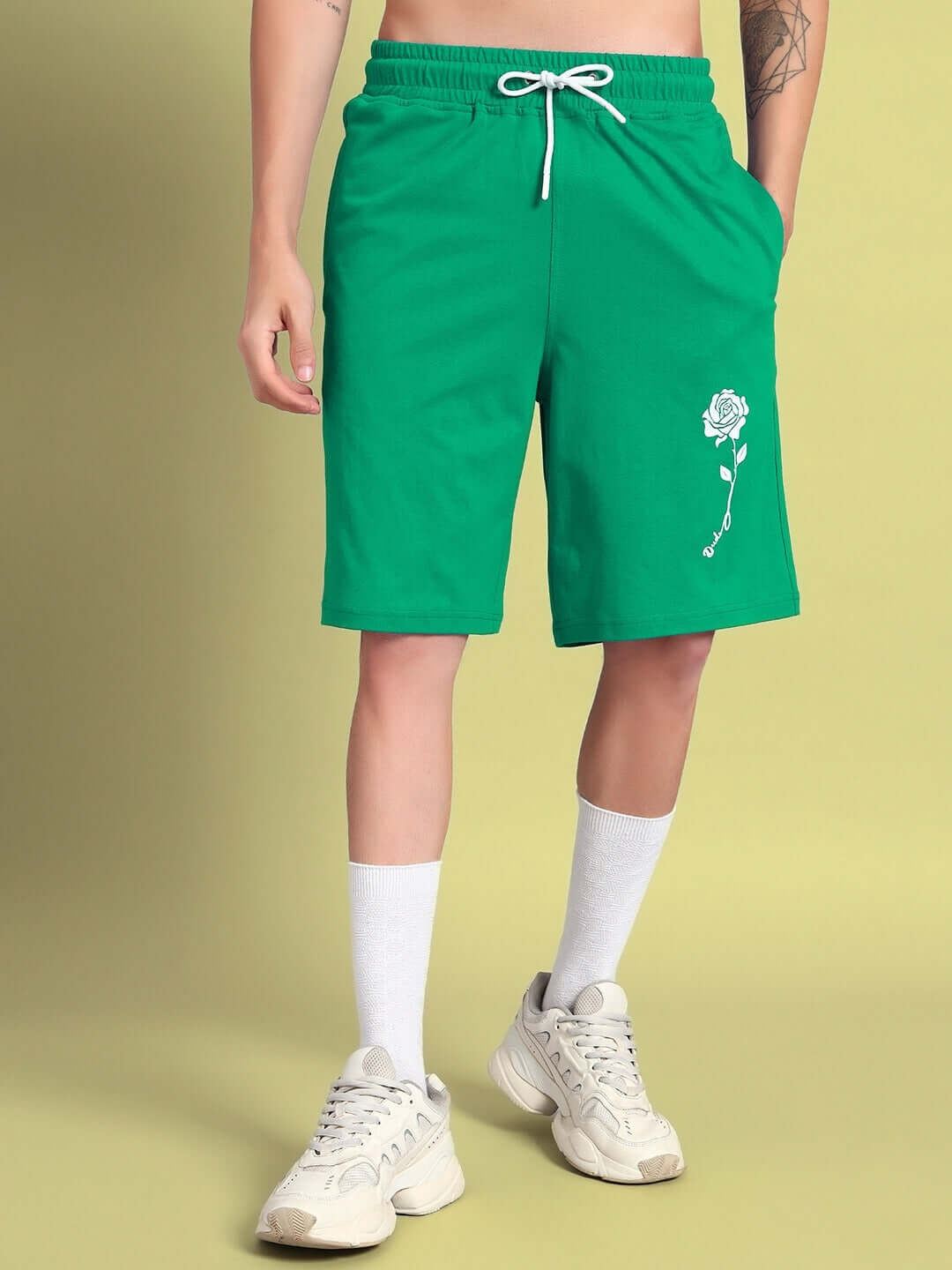 Model wearing green LIMBO CO-ORD shorts in premium cotton, featuring a rose design, ideal for casual wear. Cold machine wash recommended.