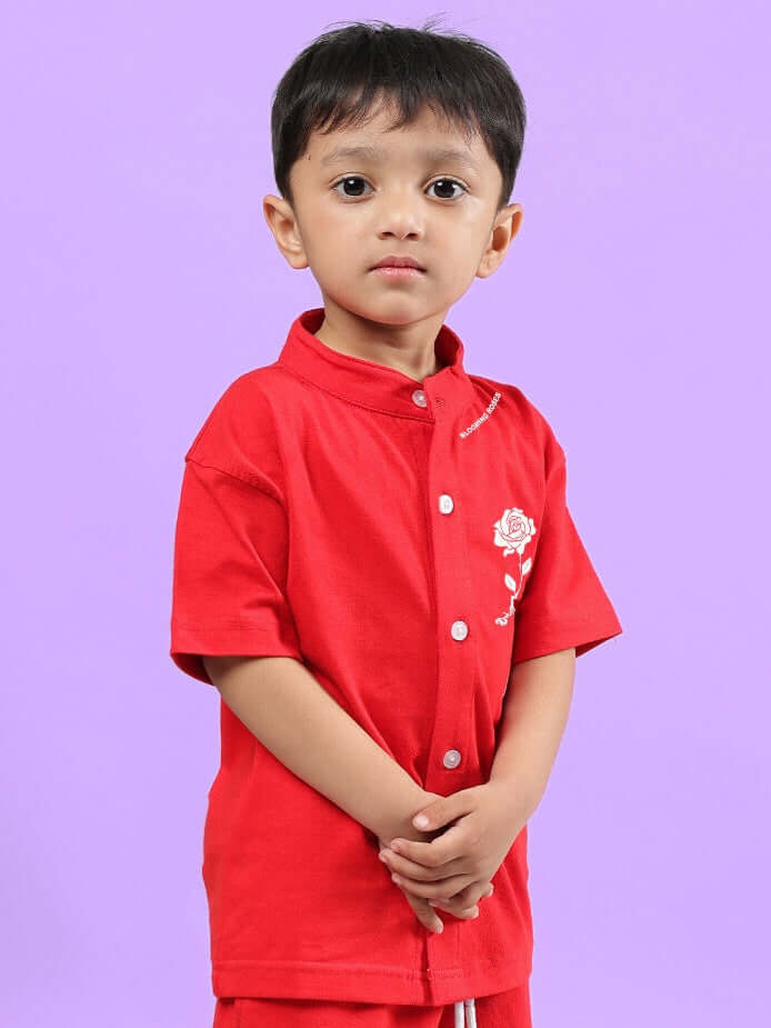 Child wearing red LIMBO shirt for boys and girls, showcasing front design with flower embroidery, against a purple background.