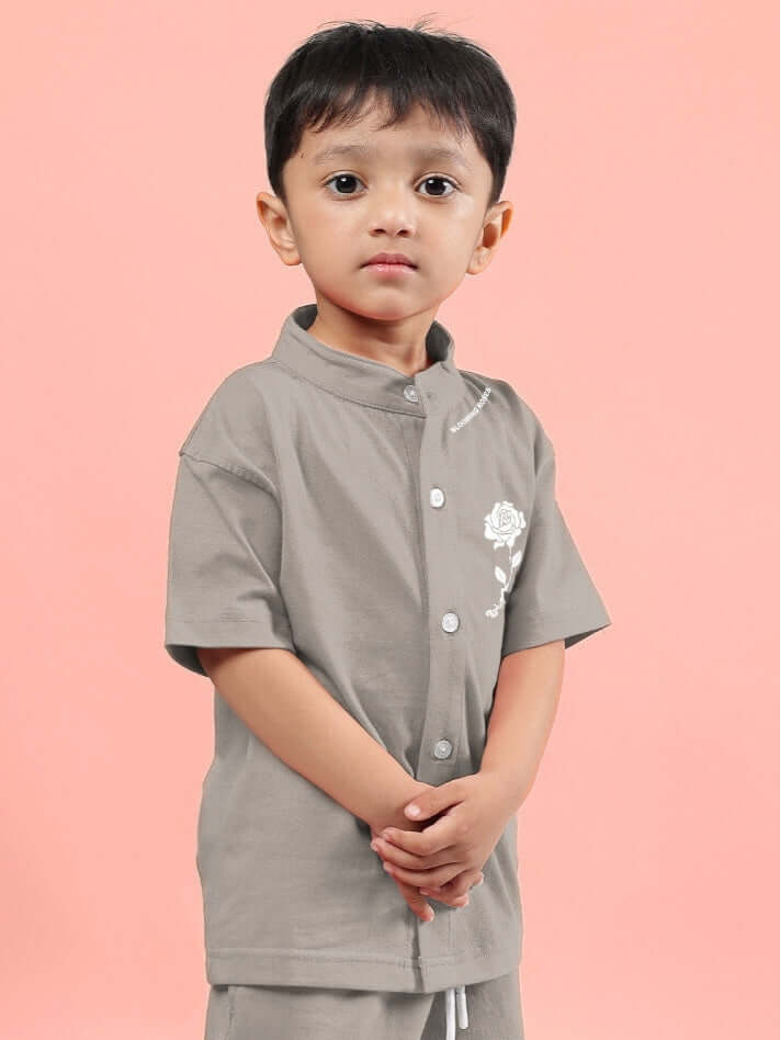 Child wearing LIMBO SHIRT FOR BOYS & GIRLS GREY, standing against a pink background.