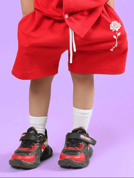Child wearing LIMBO SHORTS FOR BOYS & GIRLS RED with rose embroidery.