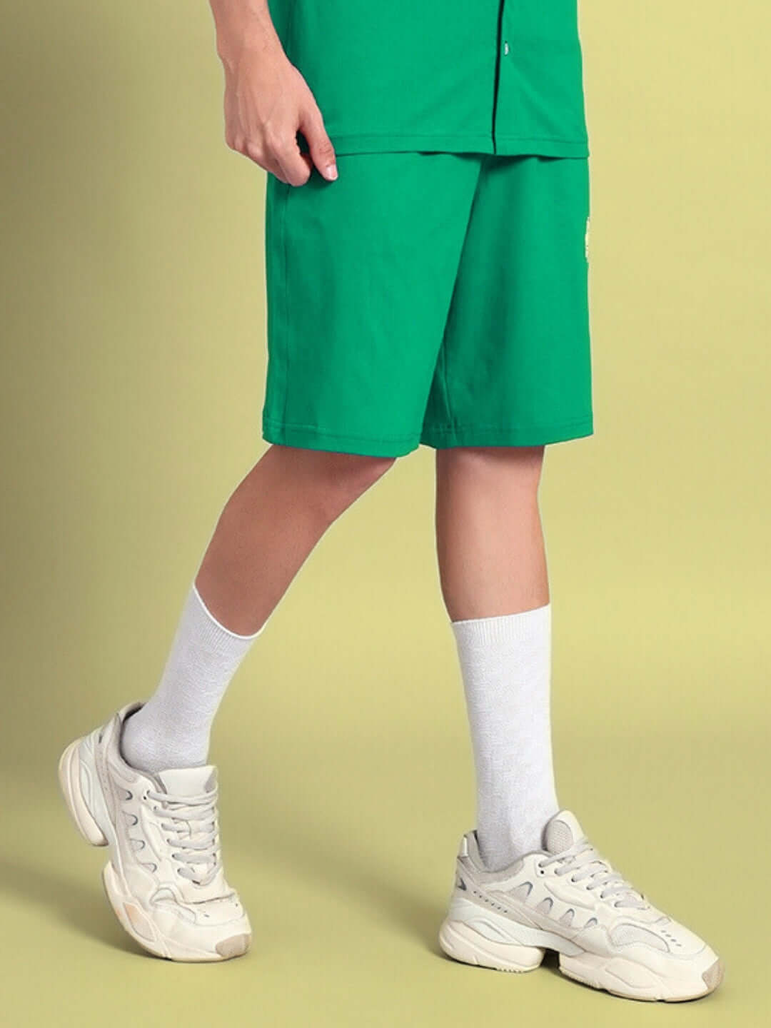 Model wearing LIMBO Summer Shorts in green, paired with white socks and sneakers, showcasing a casual summer look.