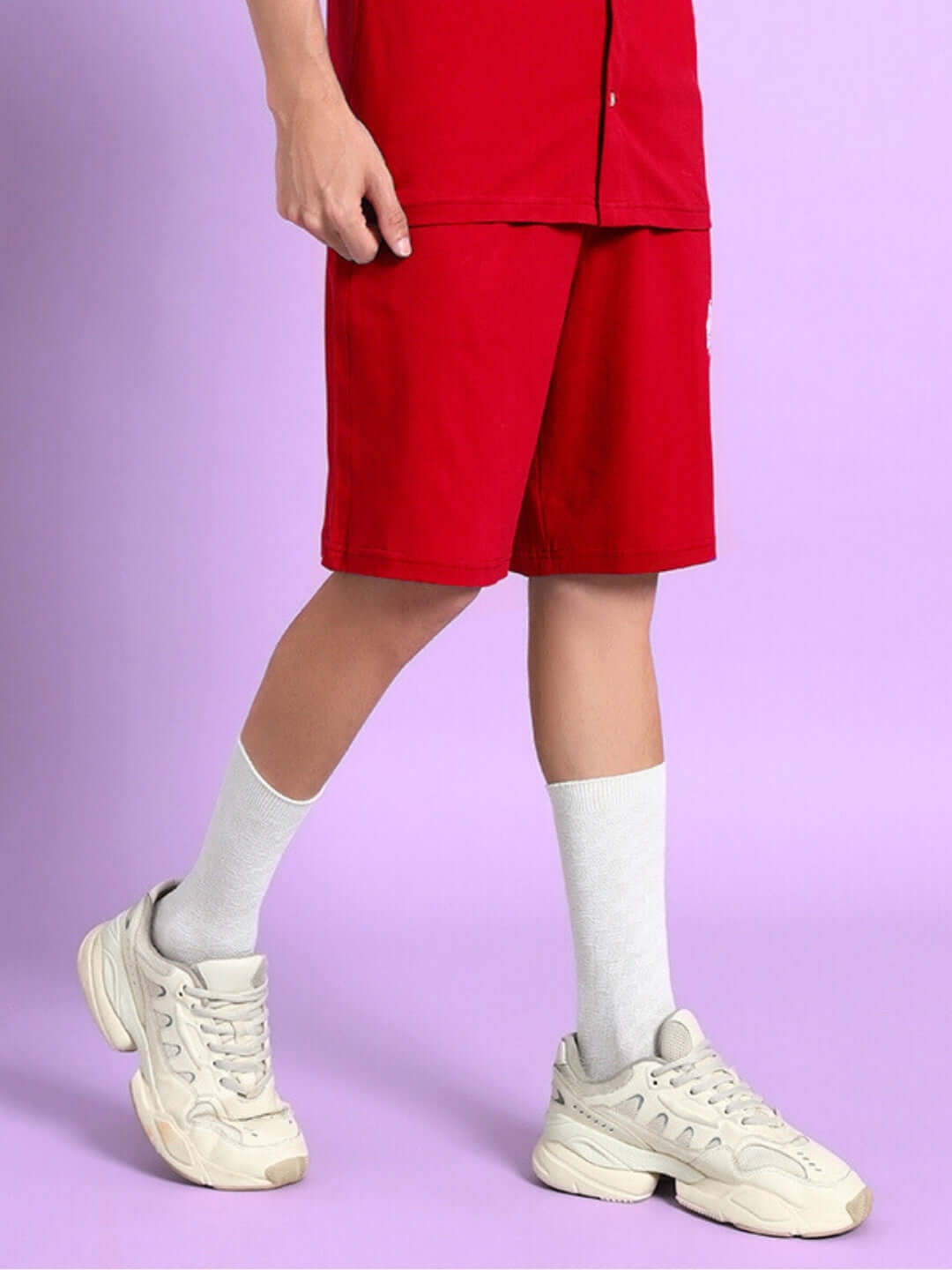 Model wearing LIMBO SUMMER COTTON SHORTS RED with white sneakers and socks, showcasing summer streetwear style.