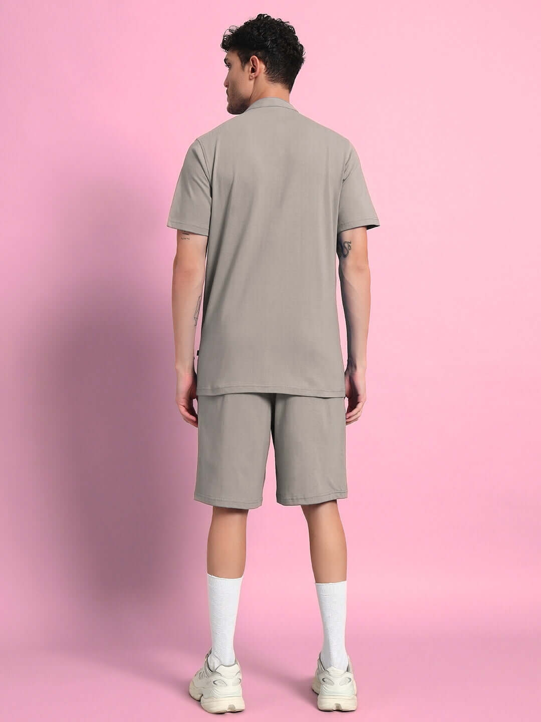 Model wearing grey LIMBO CO-ORD set, showcasing premium cotton fabric, on a pink background. Back view of shirt and shorts ensemble.