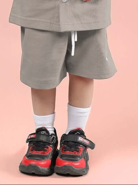 Child wearing LIMBO SHORTS FOR BOYS & GIRLS GREY with red sneakers, showcasing comfort and style for active kids.