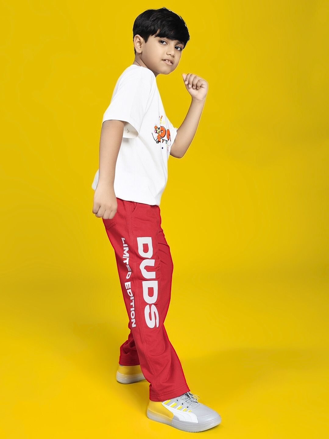 Child wearing LIMITED EDITION JOGGER FOR BOYS AND GIRLS RED in vibrant playful pose against yellow background