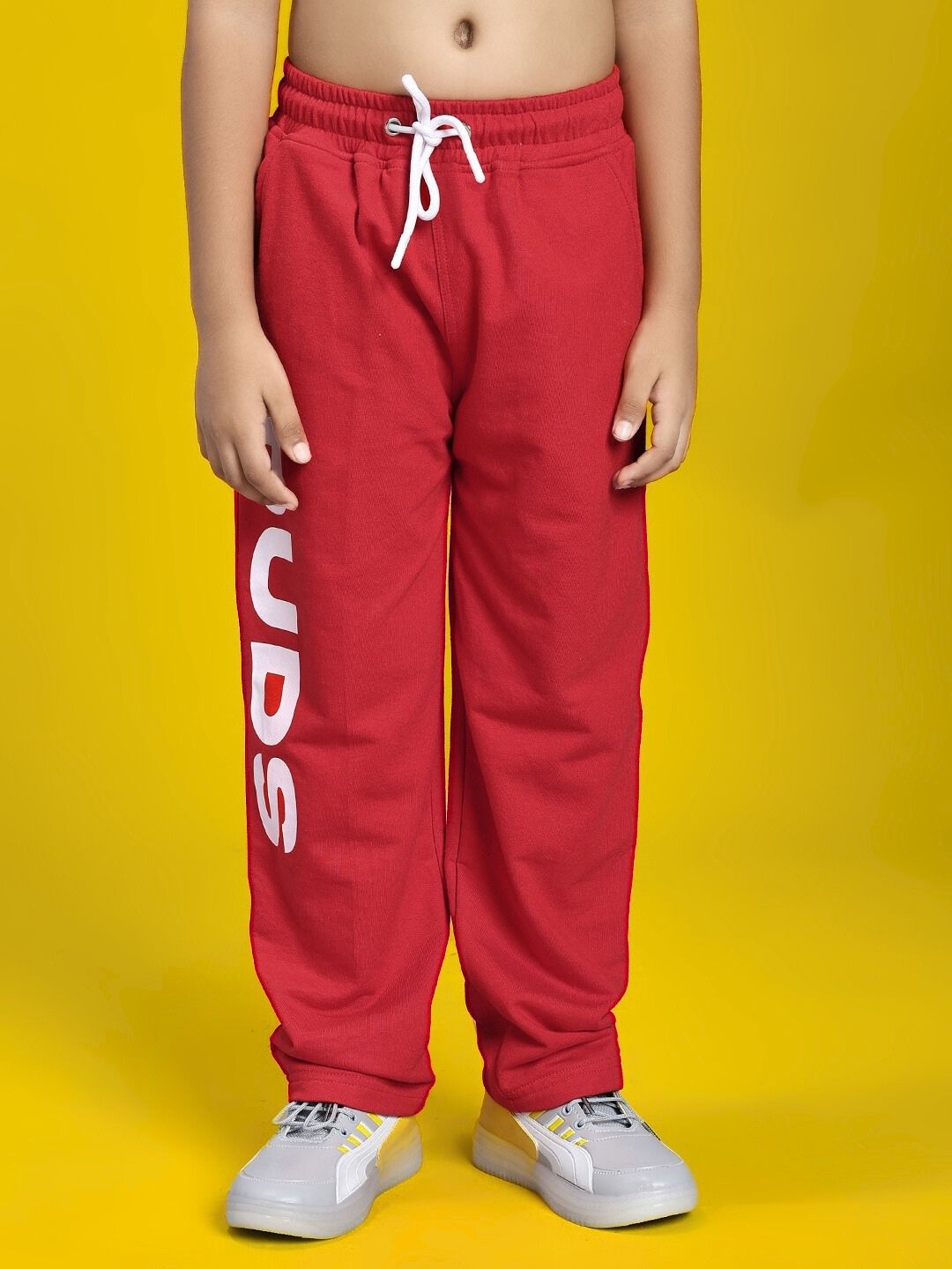 Child wearing LIMITED EDITION JOGGER FOR BOYS AND GIRLS RED, front view with yellow background, displaying comfort and style.