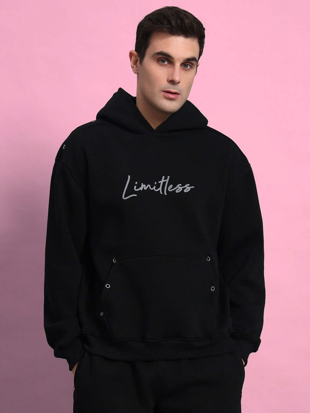 Person wearing Limitless Fleece Reflector Co-Ord Black hoodie on a pink background, showcasing style and comfort in streetwear fashion.