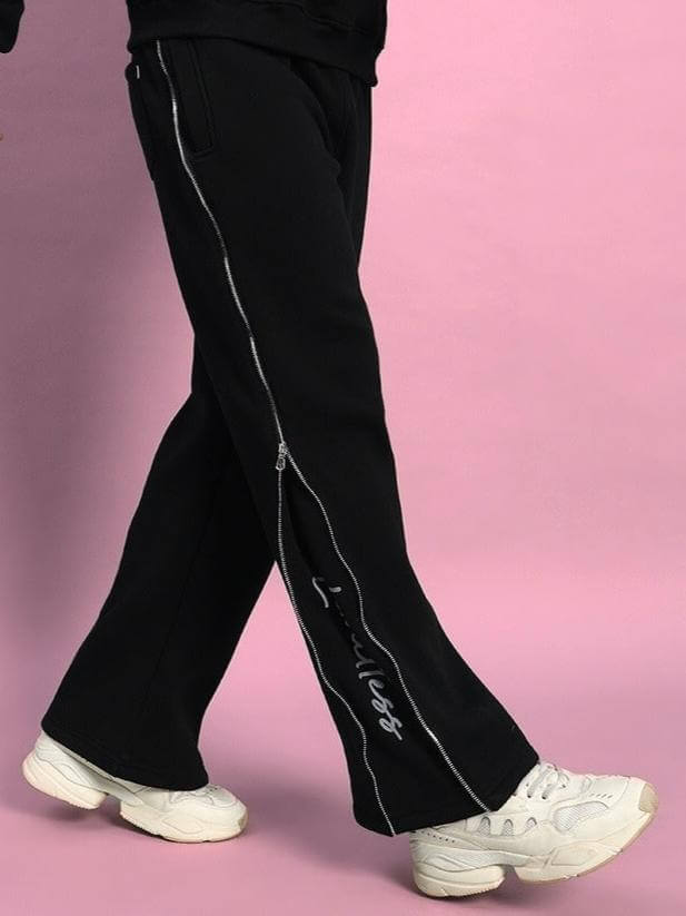 Person wearing LIMITLESS FLEECE REFLECTOR JOGGER BLACK with white sneakers on pink background