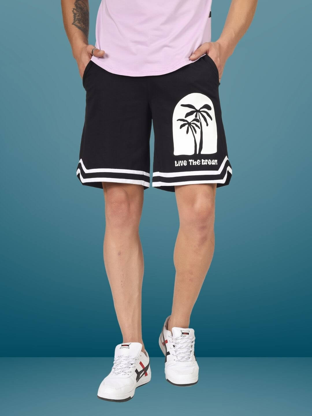 Man wearing Live the Dream regular fit black shorts with palm tree design.