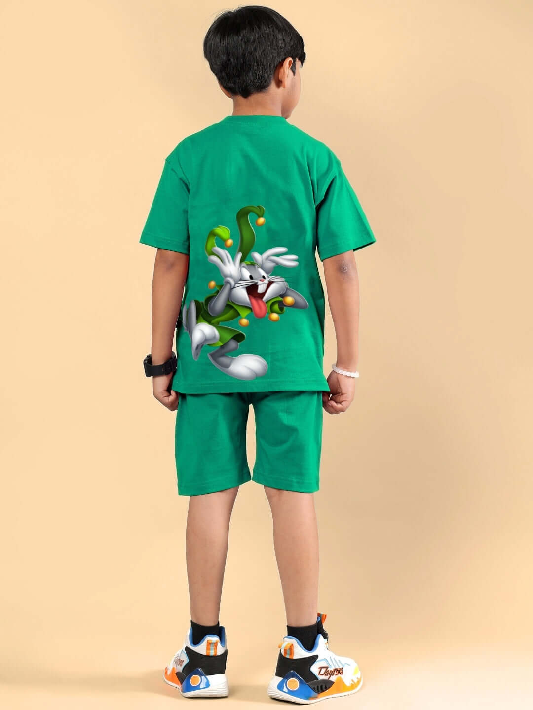 Child wearing a green Looney Tunes printed co-ord set featuring a cartoon graphic, suitable for boys and girls. DUDS made-to-order outfit.